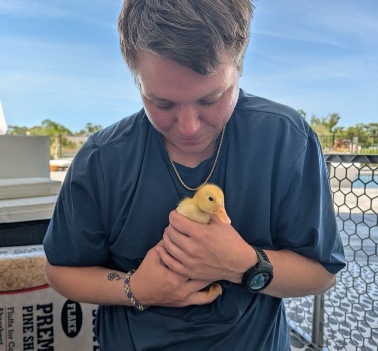 George holding a duckling against his chest