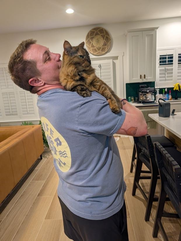 George carrying a tortoiseshell cat on his shoulder