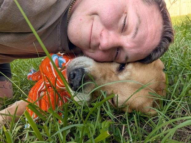 George lying in the grass with a sleepy puppy